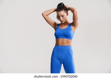 Young white fitness woman wearing sportswear standing over white wall background stretching