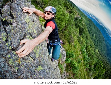 Young White Man Climbing A Steep Wall In Mountain, Rock-climb Extreme Sport, Summer Season. Horizontal Orientation