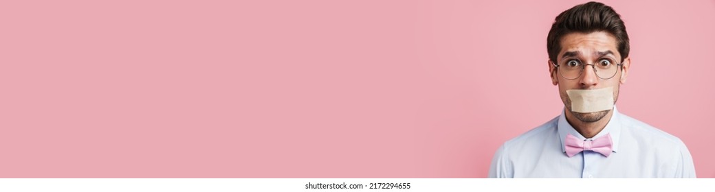 Young White Man Wearing Bow Tie Posing With Moth Glued Shut Isolated Over Pink Background