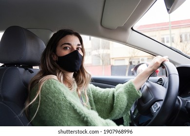 Young White Spanish Woman Wearing Protective Mask And While Driving And Green Sweater While Driving A Car Looking To Camera. Health Care, Coronavirus, Influenza And Epidemics Driving Stills.