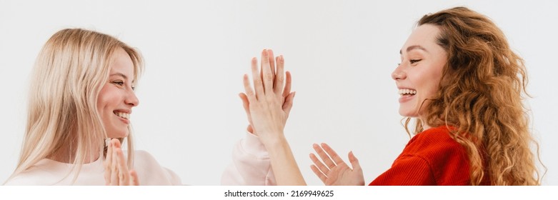 Young White Two Women Laughing While Giving High Five Isolated Over White Background