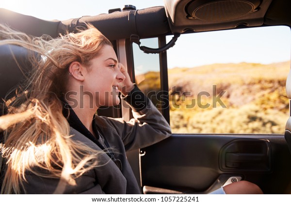 Young\
white woman admiring the scenery from an open\
car