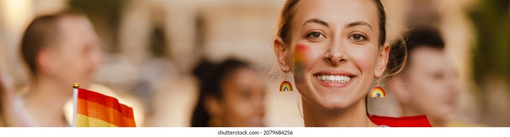 Young White Woman With Rainbow Earrings Smiling During Pride Parade Outdoors