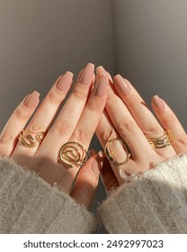 Young white woman's hands with beautiful nails and manicure wearing gold, jewelry and rings on her fingers _ Woman wearing jewelry with various beautiful manicured nails 