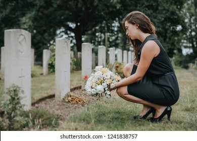 Young widow laying flowers at the grave