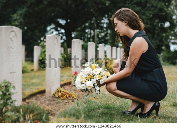 Young widow laying\
flowers at the grave
