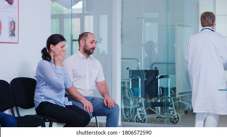 Young Wife Crying After Hearing Doctor Bad News In Hospital Waiting Room. Doctor Giving Unfavorable Test Results. Stressed Man And Woman During Medic Appointment.