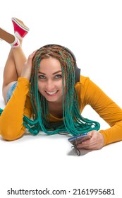 Young Winsome Positive Caucasian Female with African American Dreadlocks Listens Music in Wirreless Headphones Smartphone While Laying on Floor Over White. Vertical image