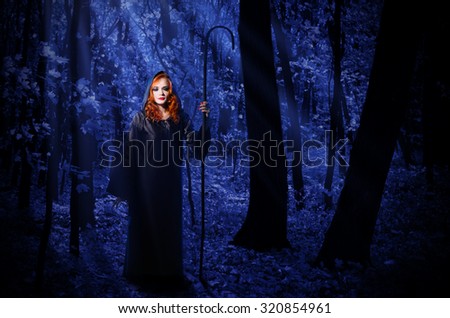 Young witch at night in the moonlight forest