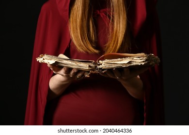 Young witch with spell book on dark background, closeup - Shutterstock ID 2040464336