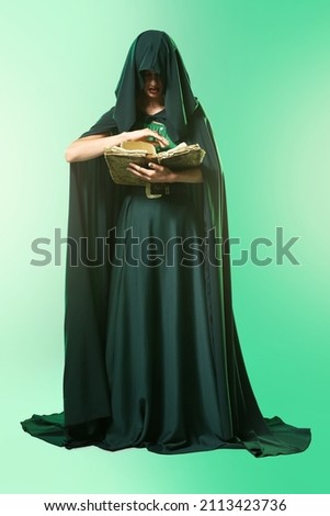 Young witch with spell book on color background