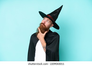 Young Wizard In Halloween Isolated On Blue Background Having Doubts