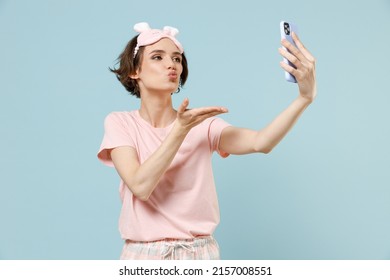 Young Woman 20s In Pajamas Jam Sleep Eye Mask Rest Relaxing At Home Doing Selfie Shot On Mobile Phone Blow Air Kiss Isolated On Pastel Blue Background Studio Portrait. Good Mood Night Bedtime Concept