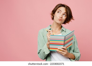 Young woman 20s she wear green shirt white t-shirt writing down in notebook diary remind memories and make list of dreams isolated on plain pastel light pink background studio People lifestyle concept - Shutterstock ID 2233002371