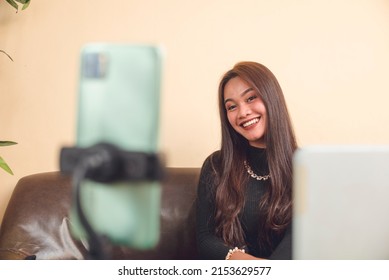 A young woman acting cute for the camera. A modern Gen-Z influencer and vlogger. Taking a picture of herself to send to her family. Giving updates about her life. - Shutterstock ID 2153629577