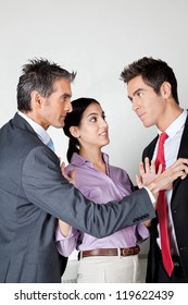 Young Woman Acting As Peacemaker Between Two Fighting Business Colleagues