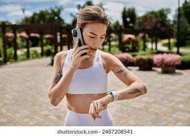 A young woman in active wear checks her smartwatch after ending a phone call while working out outdoors. - Powered by Shutterstock