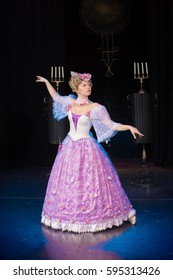 Young Woman Actress In A Medieval Pink Dress With A Puffed Skirt Is Posing Against The Backdrop Of The Scenery For The Play