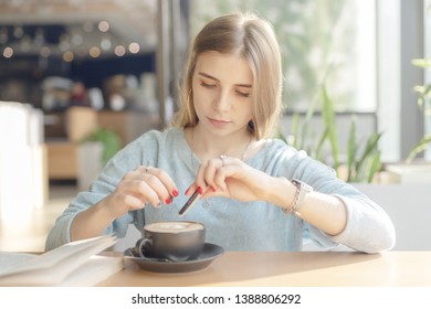 Young woman adding sugar to the coffee - Powered by Shutterstock