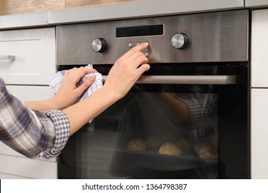 Young Woman Adjusting Oven Settings In Kitchen, Closeup