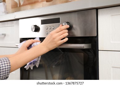 Young Woman Adjusting Oven Settings In Kitchen, Closeup