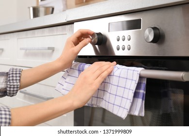 Young Woman Adjusting Oven Settings In Kitchen, Closeup