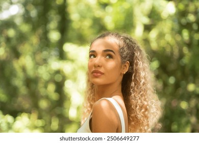 Young woman admiring nature in the forest. Thoughtful girl in athletic wear enjoying a peaceful moment outdoors - Powered by Shutterstock