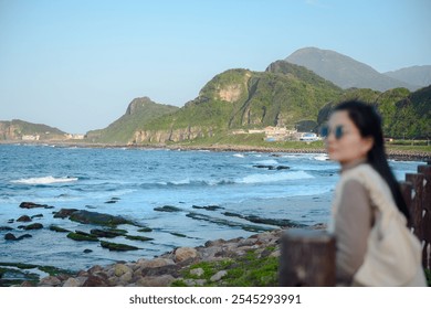 A young woman admiring the picturesque coastline with rocky beaches and verdant mountains at Yehliu Geopark in Taiwan A serene vacation spot perfect for those who enjoy the outdoors - Powered by Shutterstock