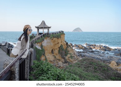 A young woman admiring the picturesque coastline with rocky beaches and verdant mountains at Yehliu Geopark in Taiwan A serene vacation spot perfect for those who enjoy the outdoors - Powered by Shutterstock