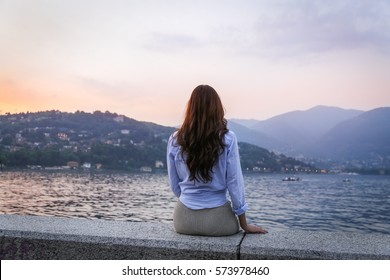 Young Woman Admiring Sunset At The Lake Como, Italy. Rear View