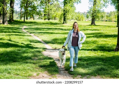 Young Woman Adopt Young Dog Labrador Retriever From Animal Rescue Center And Gave Him Love And Friendship. Female Animal Lover Spending Time With Her Puppy In The Park.