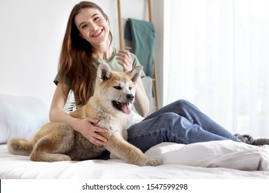 Young woman with adorable Akita Inu dog in bedroom - Shutterstock ID 1547599298