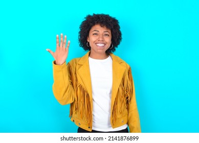 Young Woman With Afro Hairstyle Wearing Yellow Fringe Jacket Over Blue Background Smiling And Looking Friendly, Showing Number Five Or Fifth With Hand Forward, Counting Down