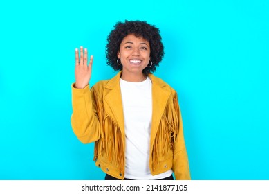 Young Woman With Afro Hairstyle Wearing Yellow Fringe Jacket Over Blue Background Smiling And Looking Friendly, Showing Number Four Or Fourth With Hand Forward, Counting Down