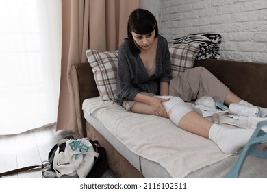 Young Woman After An ACL Surgery, Sitting On The Couch And Getting Ready To Change Her Bandage.