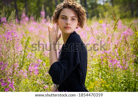 A young woman against the background of blooming Ivan-tea on a bright sunny summer day.The concept of youth