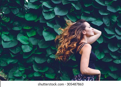 Young Woman, Against Background Of Summer Green Park, Green Leaves. Running Girl With Beautiful Curly Hair