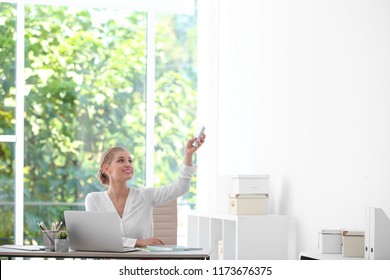 Young Woman With Air Conditioner Remote In Office