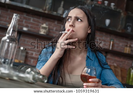 Young woman alcoholic smoker social problems concept sitting smoking cigarette looking ut the window