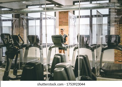 Young woman alone in the gym on the treadmill. The gym is adapted to social distancing because of the global pandemic. - Powered by Shutterstock