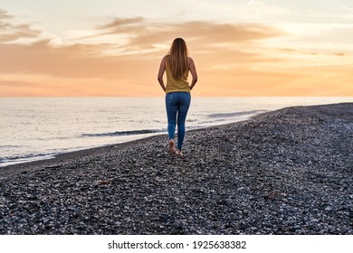 Young Woman Alone Walking On The Beach Sand At Sunset. Concept Of Relaxation And Meditation