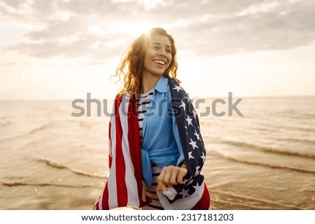 Young woman with  American flag on the beach. Patriotic holiday. USA celebrate 4th of July. Independence Day concept