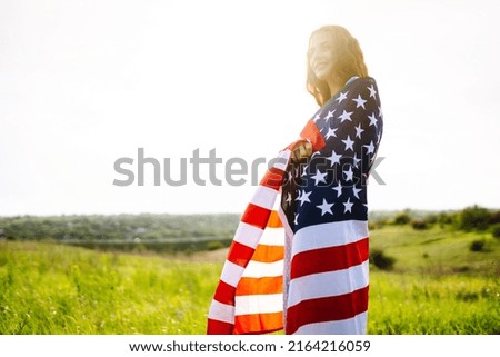 Young woman with american USA flag  on blooming meadow. Independence Day, 4th July.