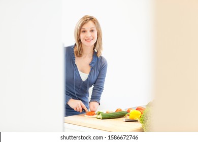 Young Woman With Amputee Arm Cutting Vegetables In Kitchen