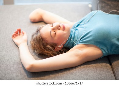 Young Woman With Amputee Arm Lying Down And Listening To