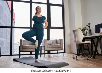 Young woman with amputee arm practicing yoga Tree pose at the self isolation at home