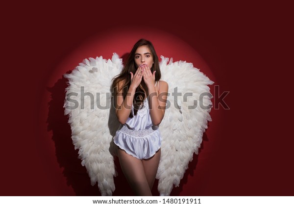 Young woman in angel costume. Valentines day and\
costumes concept. Girl with angel wings and a white dress. Fallen\
white angel. Long white\
wings