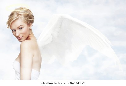 Young woman as angel with white wings in a clouds