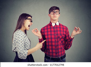 Young woman in anger yelling at boyfriend in glasses trying to keep calm in meditation