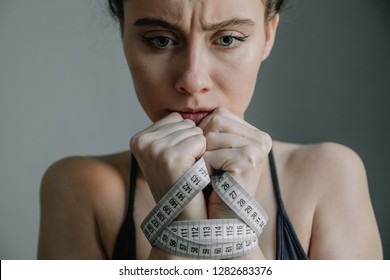 Young Woman With Anorexia And Depression With Black Suit She Is Measuring Her Body. Sadness, Nostlagic, Depression. Disgust For Eating. Mental Problems Of Young People. Close Up. Portrait.